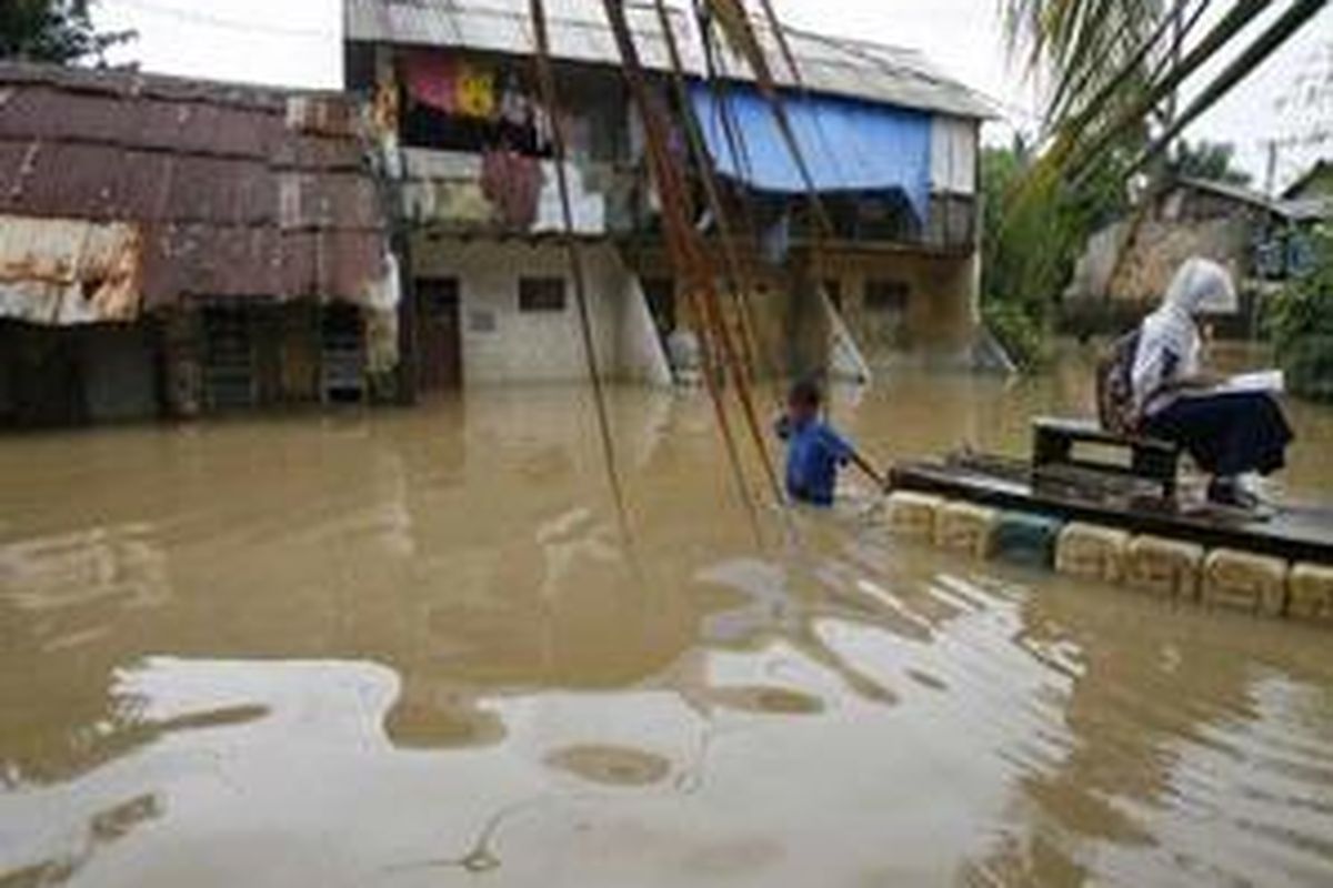 Tado mengantar cucunya, Bunga, dengan sampan menembus luapan Sungai Ciliwung di Kelurahan Cawang, Kecamatan Kramat Jati, Jakarta Timur, Rabu (14/1). Hujan yang terus mengguyur Jabodetabek membuat ratusan KK yang tinggal di kawasan rawan banjir mengungsi. 