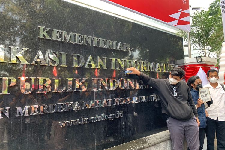 Ahmad perwakilan Blok Politik Pelajar menggelar aksi simbolis dengan menyiram gedung Kementerian Komunikasi dan Informatika dengan sebotol air seni di Jalan Medan Merdeka Barat, Senin (1/8/2022).