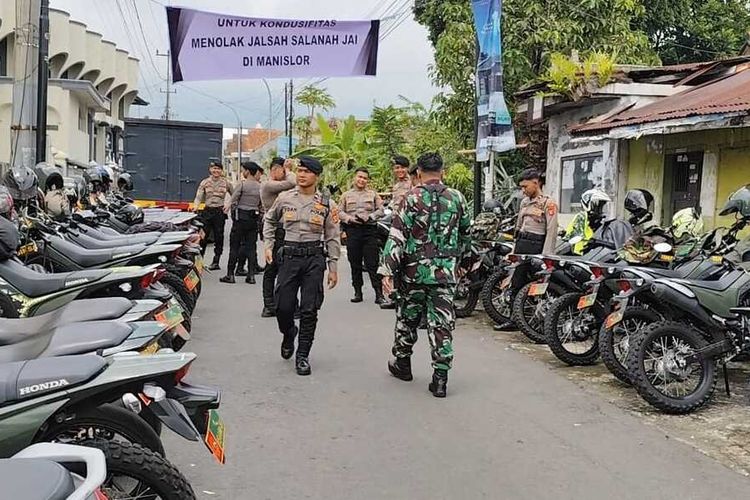 Sejumlah petugas kepolisian dan TNI berjaga di pintu masuk menuju Desa Manislor Kecamatan Jalaksana Kabupaten Kuningan Jawa Barat, Jumat (6/12/2024) siang. Tampak spanduk bertuliskan untuk kondusifitas menolak Jalsah Salanah di Manislor terbentang di pintu masuk desa.