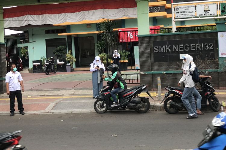 Sejumlah siswa dijemput oleh keluarga sepulang Pembelajaran Tatap Muka (PTM) Terbatas di SMKN 32, Tebet, Jakarta Selatan pada Senin (30/8/2021) siang.  Di sisi lain, siswa juga memesan ojek online untuk pulang ke rumah.