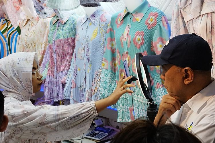 Menteri Koperasi dan UKM Teten Masduki memerhatikan pedagang yang sedang berjualan melalui siaran langsung TikTok di Pasar Tanah Abang Blok A, Jakarta Pusat, Selasa (19/9/2023). (KOMPAS.com/XENA OLIVIA)