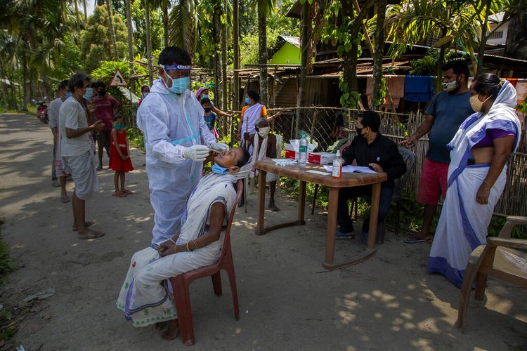 Seorang pekerja kesehatan India dengan berpakaian pelindung lengkap melakukan tes usap (swab) Covid-19 kepada warga Desa Burha Mayong, Assam, India, pada 22 Mei 2021.