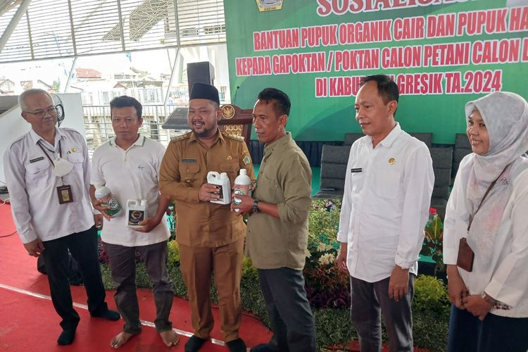 Kepala Dinas Pertanian Gresik Eko Anindito Putro (kiri) dan Bupati Gresik Fandi Akhmad Yani (tiga dari kiri), menyerahkan bantuan pupuk organik dan hayati cair kepada perwakilan petani di WEP, Gresik, Jawa Timur, Rabu (7/2/2024).