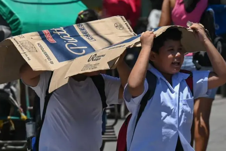 Para pelajar di ibu kota Filipina, Manila, menggunakan kotak kardus untuk melindungi diri mereka dari sinar matahari.