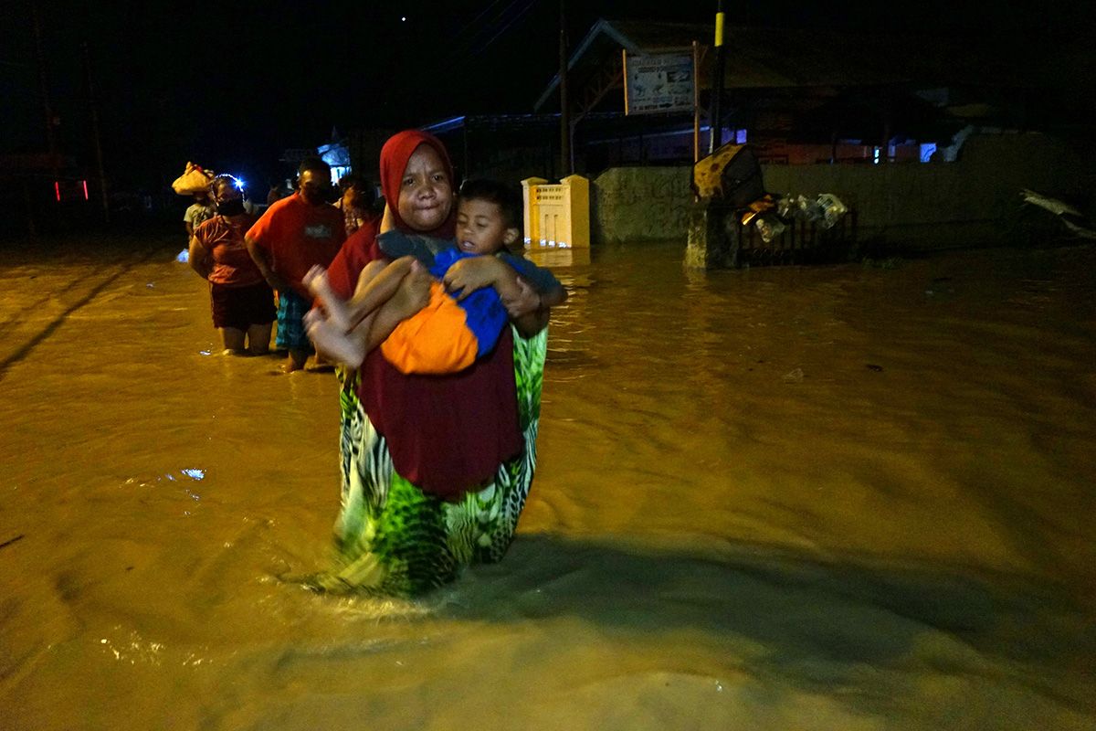 Sejumlah warga melintasi banjir untuk mengungsi ke tempat yang lebih tinggi di Kota Timur, Kota Gorontalo, Gorontalo, Kamis (11/6/2020) malam. Data sementara dari pemerintah setempat mencatat sebanyak 1.150 warga terdampak banjir dengan ketinggian air mencapai 1,5 meter.
