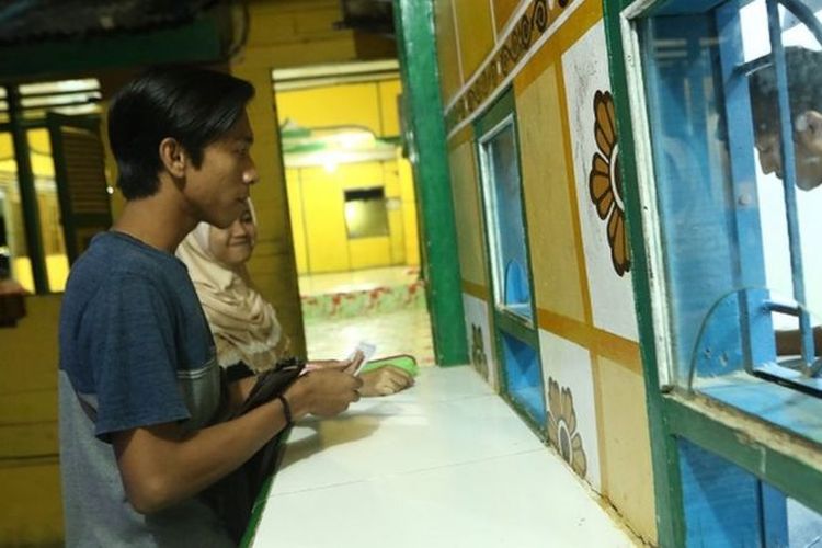 Seorang warga menyetor hasil penjualan ternak ikan lele ke Baitul Mal Kampung Matfa.