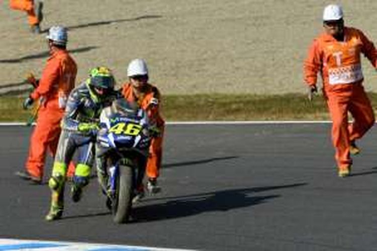 Pebalap Movistar Yamaha MotoGP asal Italia, Valentino Rossi, mencoba menyalakan motornya dengan bantuan para marshal setelah terjatuh saat menjalani balapan GP Jepang di Sirkuit Twin Ring Motegi, Minggu (16/10/2016).