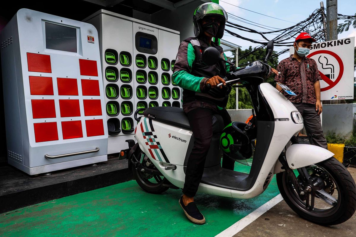 Pengemudi ojek daring mengganti baterai sepeda motor listrik dengan yang sudah penuh terisi di Stasiun Penukaran Baterai Kendaraan Listrik Umum (SPBKLU) di SPBU Pertamina, Jalan MT Haryono, Jakarta, Senin (28/3/2022). Pemerintah Indonesia menargetkan dua juta kendaraan listrik dapat digunakan oleh masyarakat Indonesia pada 2025 sebagai salah satu upaya untuk menerapkan penggunaan energi terbarukan.