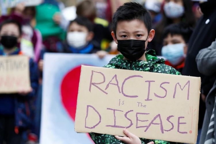 Ethan Yang, 11, memegang tanda bertuliskan rasisme adalah penyakit selama unjuk rasa Anak vs. Rasisme melawan kejahatan rasial anti-Asia di Hing Hay Park di Chinatown-International District of Seattle, Washington, AS, 20 Maret 2021.