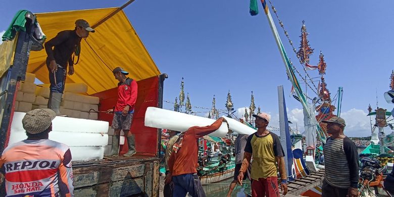 Buruh angkut di Pelabuhan Muncar Banyuwangi membawa balok ke ke kapal yang akan berlayar mencari ikan pada Selasa (14/3/2023)