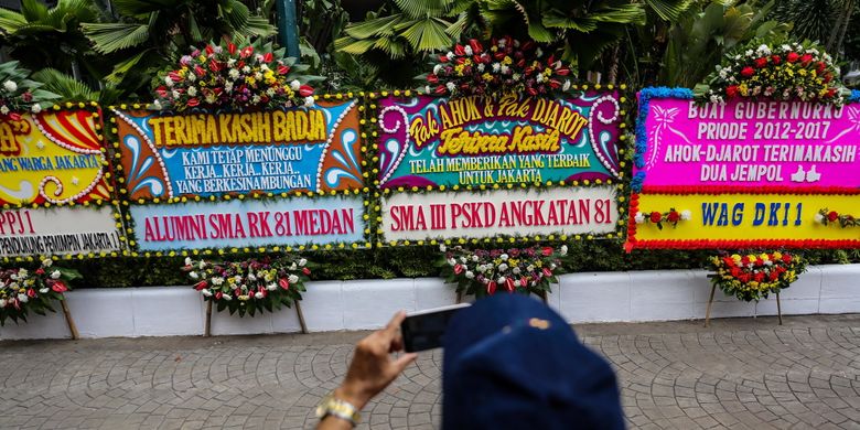 Warga memotret karangan bunga yang ditujukan untuk Basuki Tjahaja Purnama atau Ahok dan Djarot Saiful Hidayat di kompleks Balai Kota DKI Jakarta, Senin (9/10/2017). Karangan bunga tersebut berisi ucapan terima kasih dari warga atas kepemimpinan Basuki dan Djarot selama berpasangan menjadi gubernur dan wakil gubernur DKI Jakarta.