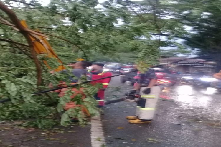 Hujan deras disertai angin kencang menyebabkan pohon tumbang menimpa kabel listrik dan sebuah warung di depan RM Tirta Raya, Jalan Raya Muchtar, Kelurahan Sawangan Baru, Kecamatan Sawangan, Kota Depok, Minggu (9/10/2022).