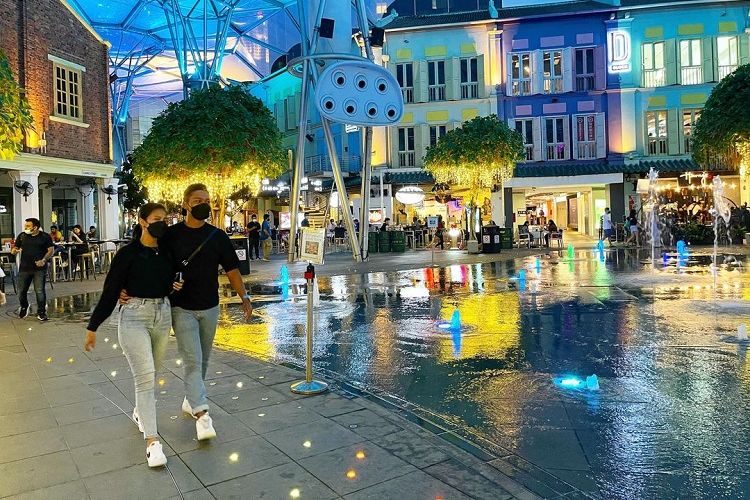 Pasangan muda-mudi Singapura sedang melintas di depan air mancur di distrik Clarke Quay, Singapura Tengah, yang terkenal akan hiburan dunia malamnya, Sabtu (26/2/2022) malam. Singapura mengumumkan pelonggaran protokol kesehatan (prokes) Covid-19 mulai Selasa (15/3/2022).