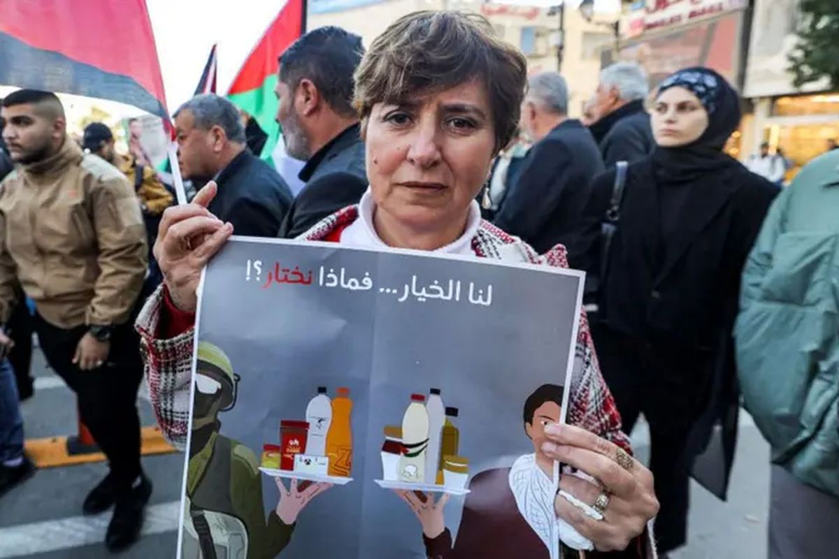 Seorang perempuan membentangkan poster berisi seruan boikot produk-produk Israel dalam demonstrasi di Ramallah, Tepi Barat, Desember 2023 lalu.