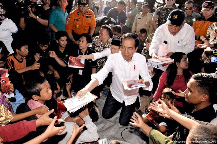 Presiden Joko Widodo membagikan buku tulis bagi anak-anak korban gempa di Desa Madayin, Kecamatan Sambelia, Kabupaten Lombok Timur, NTB, Senin (30/7/2018).