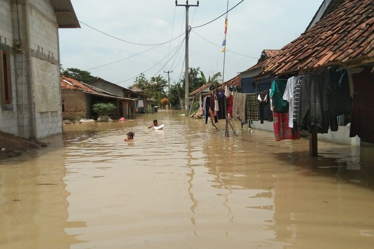 Anak - anak Kampung Pengasinan, Desa Karangligar, Kecamatan Telukjambe Barat, Kabupaten Karawang tengah beraktivitas di sela banjir, Senin (8/11/2021).