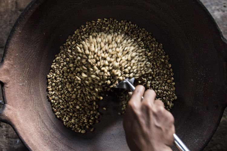 Rizki, putra dari Sahnawi, menyangrai biji kopi di Desa Gombengsari, Banyuwangi, Jawa Timur, Jumat (22/6/2018). Kopi Gombengsari yang dikenal dengan kopi robusta berkualitas terbaik memiliki ciri aroma khas buah kelapa dan cara memasaknya yang berbeda yaitu menyangrai dengan kuali tanah liat dan menumbuk biji kopi dengan kayu hingga jadi bubuk.