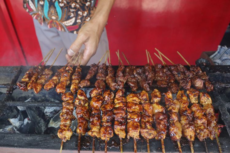 Ilustrasi sate ayam madura sedang dibakar. 