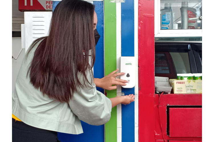 Jolene sedang mencoba dispenser manual Antis Hand Sanitizer di SPBU MT Haryono. 