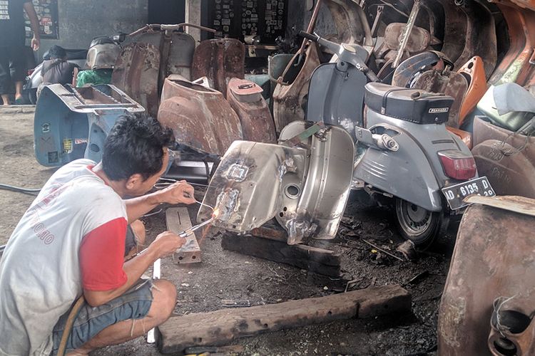 Seorang pekerja melakukan pengelasan bodi vespa di bengkel restorasi vespa Lik Mul di Solo.