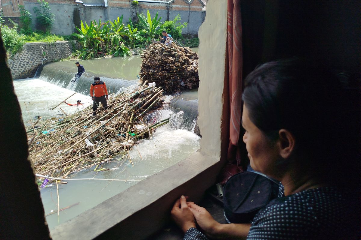 Siti Marfuati sedang melihat proses pembersihan rumpun bambu yang menyebabkan banjir di lingkungan rumahnya. 