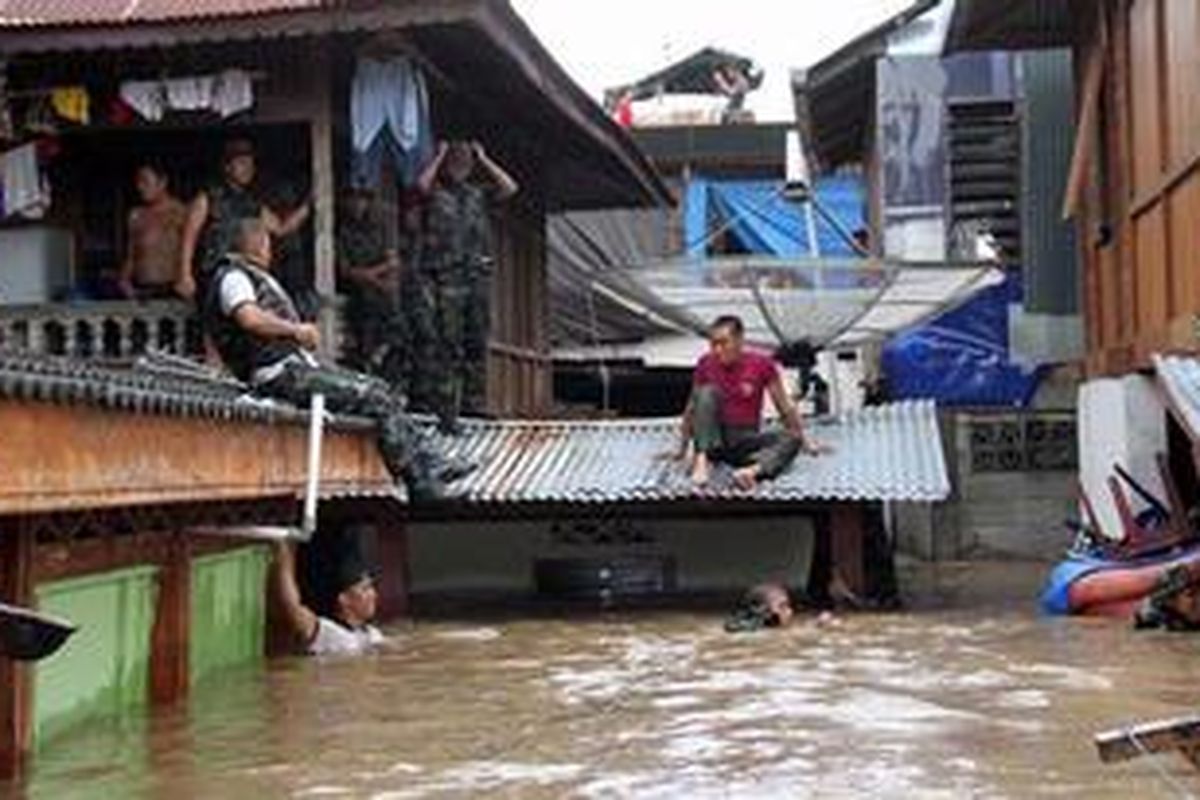 Anggota TNI berusaha menolong warga yang terjebak banjir di Manado.