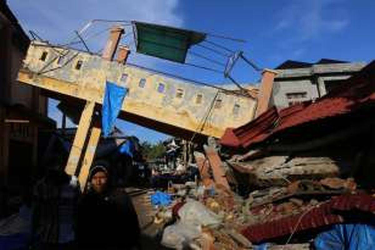 Warga melintasi bangunan pasar Meureudu yang roboh akibat bencana gempa di Kecamatan Meureudu, Kabupaten Pidie jaya, Aceh, Kamis, (8/12/2016). Sebagian korban sudah teridentifikasi dan sebagian lagi masih dalam proses pendataan serta korban luka sendiri berjumlah 128 orang luka berat, dan 489 orang luka ringan, 86 unit rumah, 105 ruko, 13 unit masjid rusak berat.