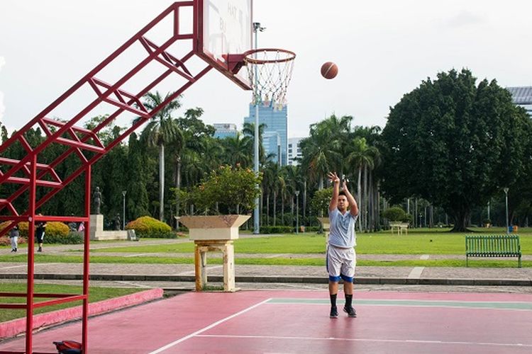 Seorang pengunjung yang datang sore hari ke Monas untuk menikmati fasilitas lapangan basket gratis, Jakarta, Rabu (29/1/2020).