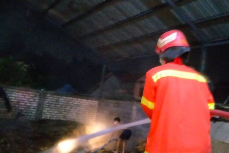 Pembasahan dilakukan petugas Damkarla Gresik Pos Driyorejo, usai kebakaran yang terjadi di gudang kertas di Desa Slempit, Kecamatan Kedamean, Gresik, Jawa Timur, Rabu (4/1/2023).