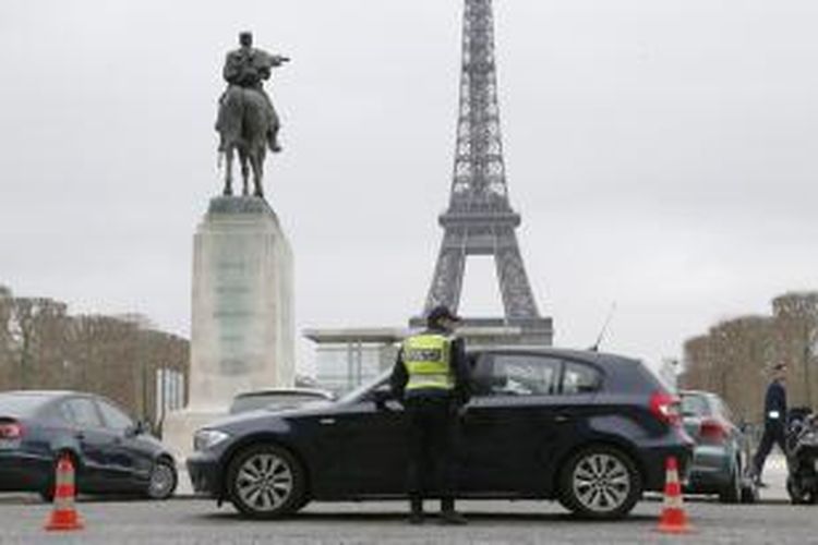 Seorang polisi lalu lintas Perancis memeriksa sebuah mobil yang melintas di ruas jalan dekat Menara Eiffel, Paris. Akibat tingkat polusi yang berbahaya, pemerintah Perancis memutuskan membatasi penggunaan mobil pribadi di Paris.