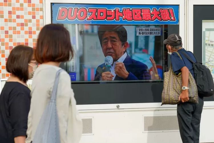 Orang-orang menyaksikan berita pembunuhan Shinzo Abe di televisi, di jalanan Tokyo.