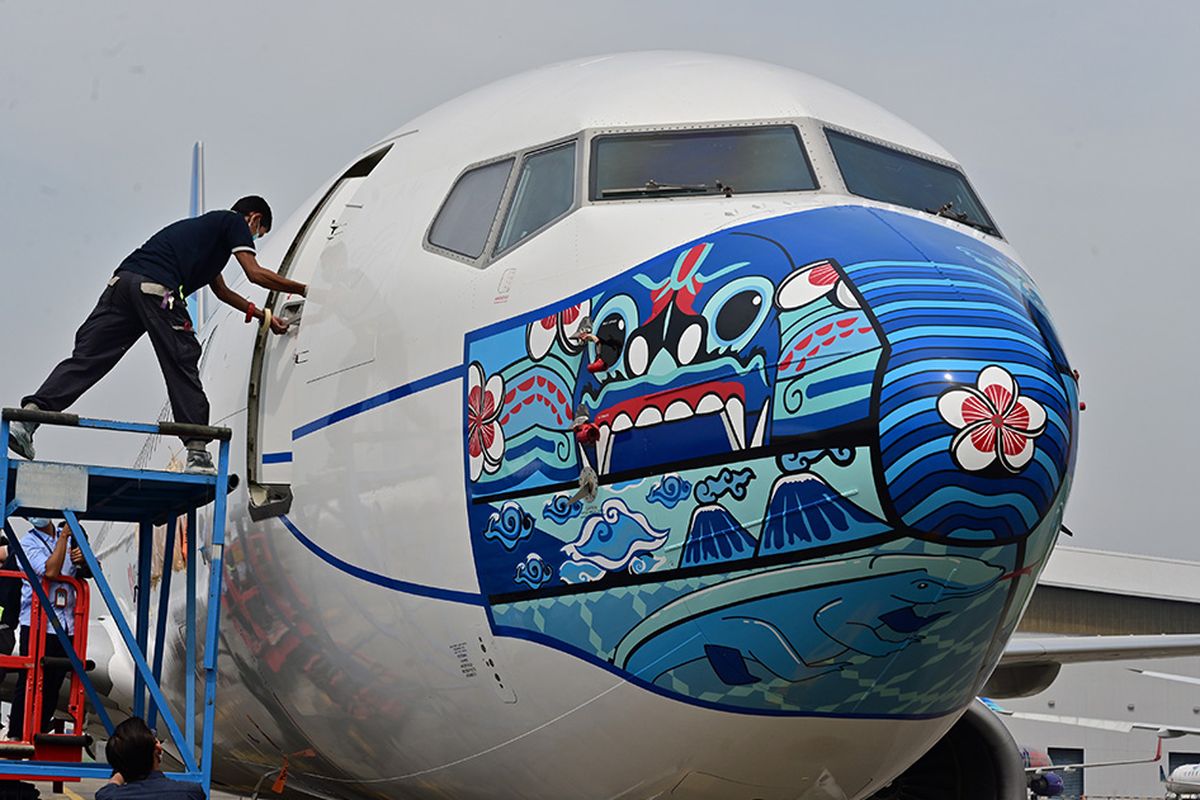 Pesawat Garuda Indonesia Boeing 373-800 NG dengan desain masker di bagian depan pesawat, saat diparkir di lapangan udara di Tangerang, Banten, Senin (12/10/2020). Pemasangan masker di pesawat tersebut digelar untuk mendukung kampanye Gerakan Ayo Pakai Masker dalam rangka penanggulangan pandemi Covid-19.
