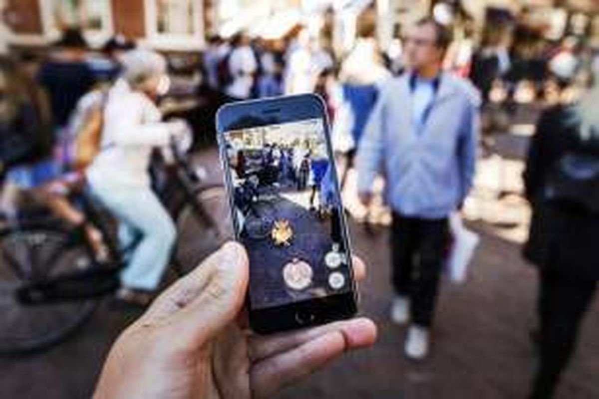 Gamer bermain dengan aplikasi Pokemon Go di ponsel mereka, di Grote Markt di Haarlem, Rabu (13/7/2016).