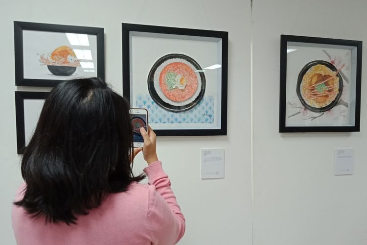 Salah seorang pengunjung tengah mengabadikan karya lukisan pada Pemeran Ilustrasi Makanan Jepang bertajuk Ceritamakan dalam rangkaian Japanese Cultural Week 2018 di Japan Foundation, Jakarta, Senin (19/2/2018).