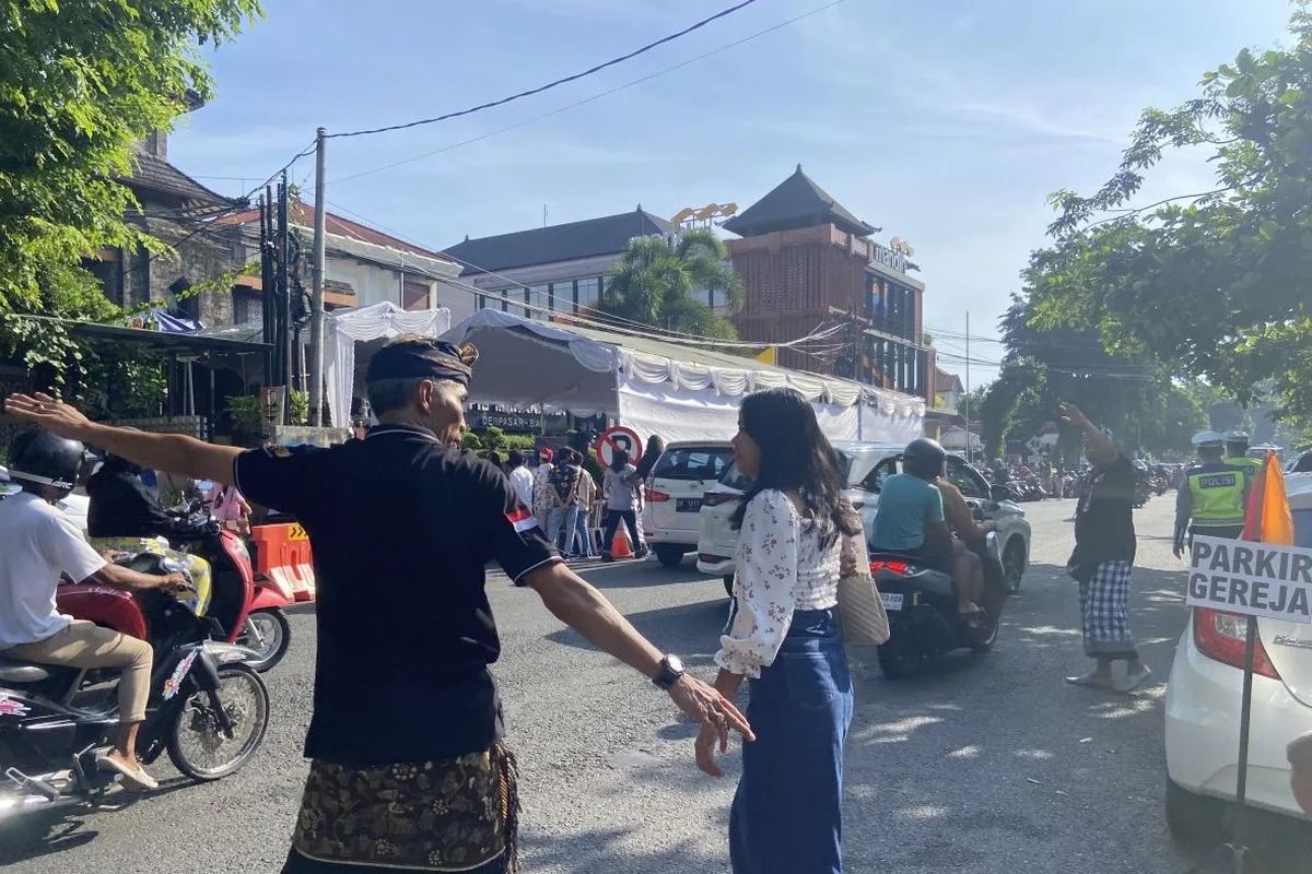 Pecalang di Desa Pakraman membantu anggota jemaat menyebrangi jalan untuk menuju ke GPIB Maranatha guna menghadiri perayaan Natal 2023 di Kota Denpasar, Provinsi Bali, Senin (25/12/2023). (ANTARA/Ni Putu Putri Muliantari)