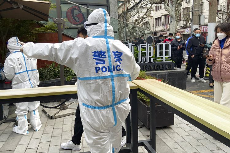 Police officers in protective gear guide residents lining up for Covid tests in the Jingan district of western Shanghai, China, Friday, April 1, 2022. As residents of western Shanghai start a four day lockdown for mass testing, some in eastern Shanghai about to end their lock down are being told they will be confined to their homes for at least 10 more days. It was the latest wrinkle in the lockdown of China's largest city as it struggles to eliminate an omicron-driven coronavirus outbreak under China's zero-Covid policy. (AP Photo/Chen Si)