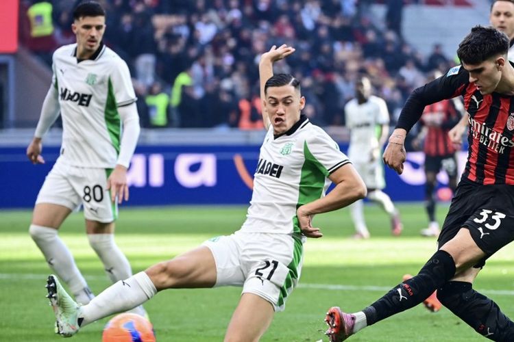 Jay Idzes (kiri) mencoba membendung tembakan Davide Bartesaghi (kanan) dalam laga Liga Italia 2025-2026 AC Milan vs Sassuolo di Stadion San Siro, 14 Desember 2025. (Photo by Piero CRUCIATTI / AFP)