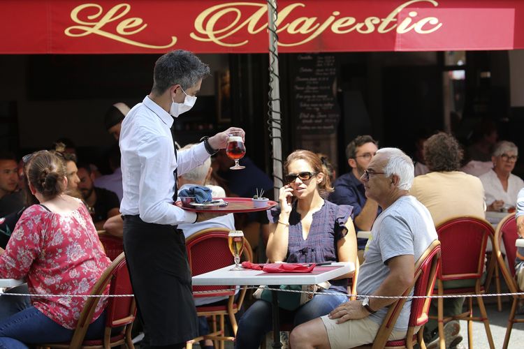 Seorang pelayan membawakan minuman untuk pengunjung sebuah kafe di Saint Jean de Luz, Perancis, Selasa (2/6/2020).
