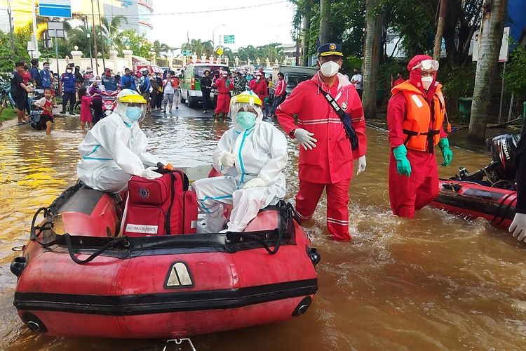 Petugas dari Suku Dinas Penanggulangan Kebakaran dan Penyelamatan Jakarta Timur mengevakuasi seorang warga Cipinang Muara terkonfirmasi positif Covid-19 yang tersampak banjir pada Sabtu (20/1/2021).