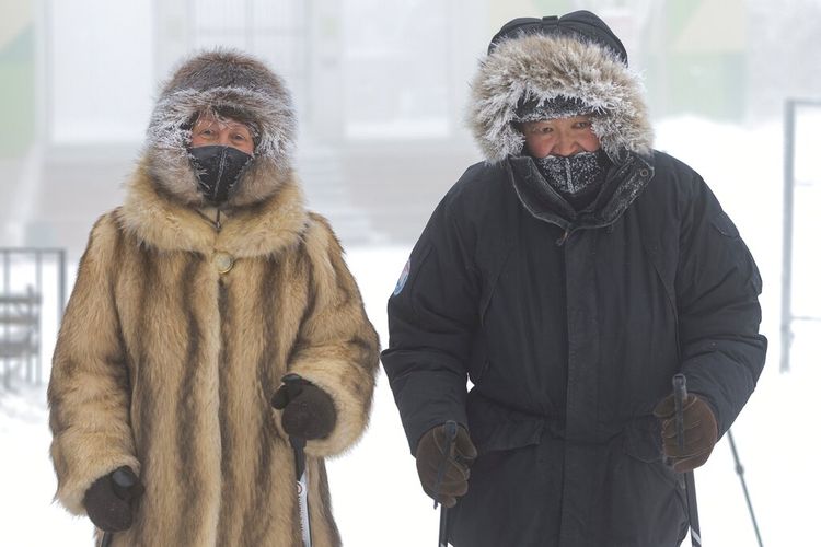 Sepasang suami istri berjalan dengan pakaian tebal di jalan saat suhu turun menjadi sekitar minus 50 derajat Celsius di Yakutsk, Rusia, Sabtu, 16 Januari 2021. 