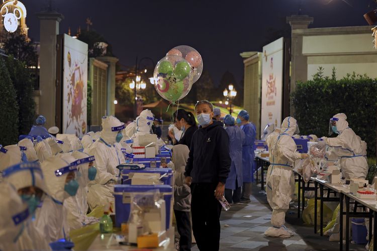 A file photo of a child holds Mickey Mouse balloons as visitors receive Covid-19 tests at the Shanghai Disney Resort in Shanghai, China on Sunday, Oct. 31, 2021. Fireworks boomed as the visitors at Shanghai Disneyland waited for their Covid-19 test results, surrounded by healthcare workers dressed from head to toe in the white protective suits. Shanghai Disneyland suddenly announced Sunday evening that they were no longer accepting any visitors and they were cooperating with an epidemiological investigation from another province. They then locked down the park, as Shanghai city healthcare workers and police rushed to the scene to conduct a mass testing. (Chinatopix via AP)