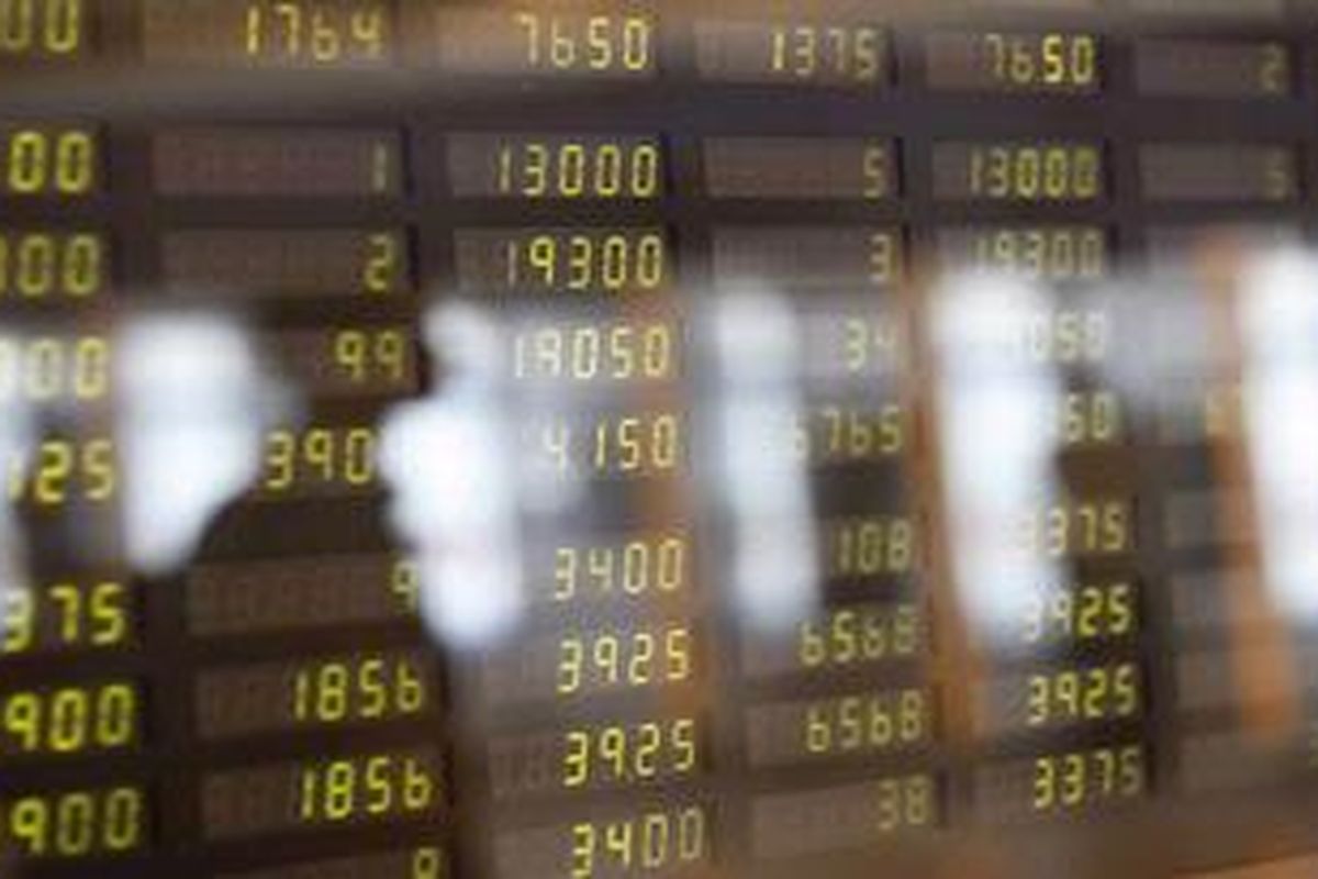 Refleksi pengunjung di papan indeks harga saham gabungan (IHSG) di Mandiri Sekuritas, Jakarta, Jumat (13/4/2012). 