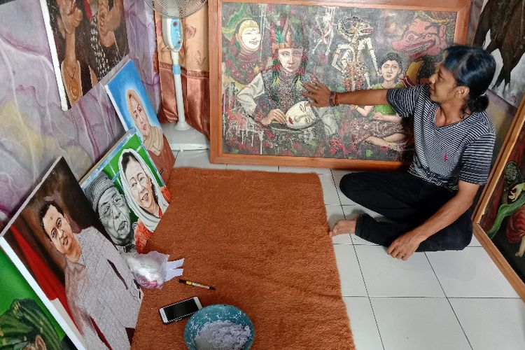 Teguh Tetris, pelukis asal Jombang, Jawa Timur, menunjukkan lukisan yang dibuat dengan memanfaatkan limbah kertas.
