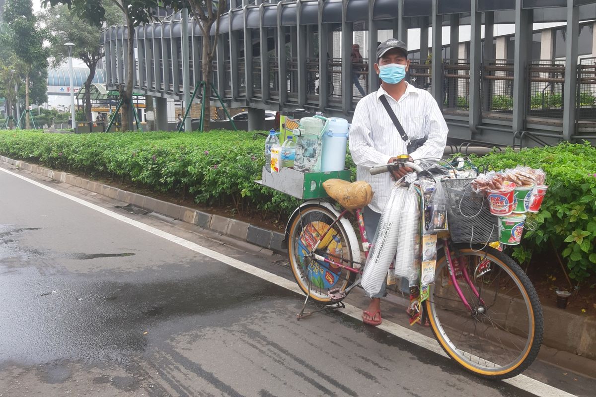 Zaini, salah seorang penjual kopi keliling saat melintas di jalur sepeda terproteksi di Jalan Sudirman, Jakarta, Sabtu (29/5/2021).