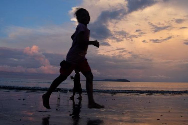 Anak-anak Desa Barawai bermain di pantai saat matahari mulai tenggelam. 
