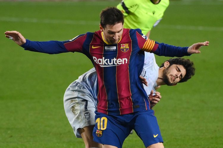 Penyerang Barcelona asal Argentina, Lionel Messi, bersaing dengan pemain depan Valencia asal Portugal Goncalo Guedes selama pertandingan sepak bola liga Spanyol antara FC Barcelona dan Valencia CF di stadion Camp Nou di Barcelona pada 19 Desember 2020.