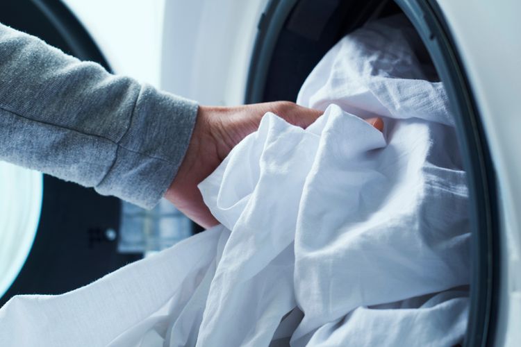 Ilustrasi mencuci seprai putih di mesin cuci. 