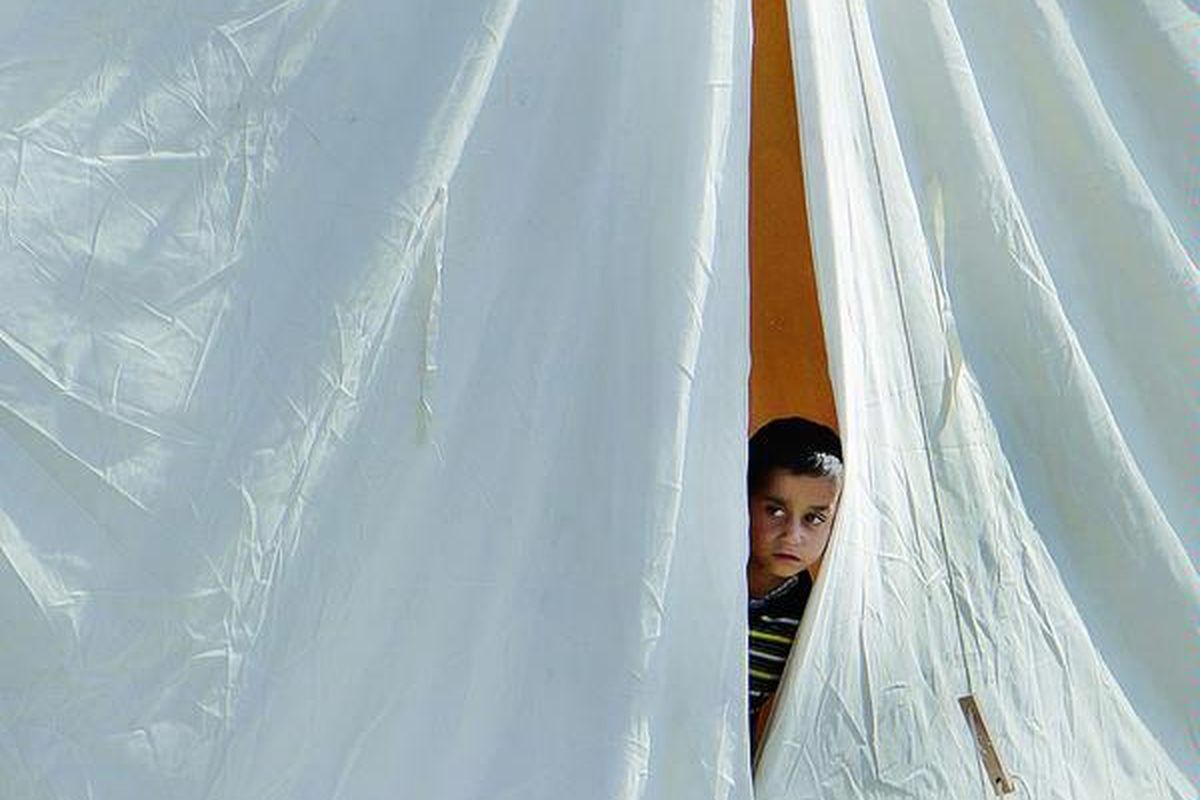 Seorang anak laki-laki pengungsi dari Suriah mengintip dari balik tenda penampungan pengungsi di Boynuyogun, Turki, Selasa (14/6). Menurut kantor Perdana Menteri Turki, jumlah pengungsi Suriah yang berada di Turki sudah mencapai lebih dari 8.500 orang. Mereka mengungsi setelah situasi di Suriah makin gawat seiring dengan peningkatan operasi penumpasan pembangkang oleh militer Suriah.