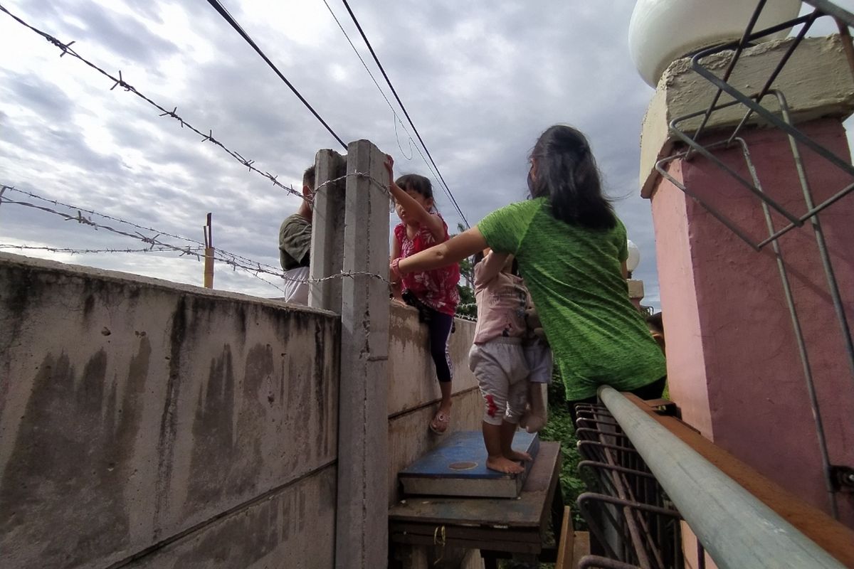 Salah satu anak kecil yang menetap di gedung fitness milik keluarga Asep harus melewati dinding berkawat duri saat hendak memasuki kediaman mereka, Minggu (14/3/2021).