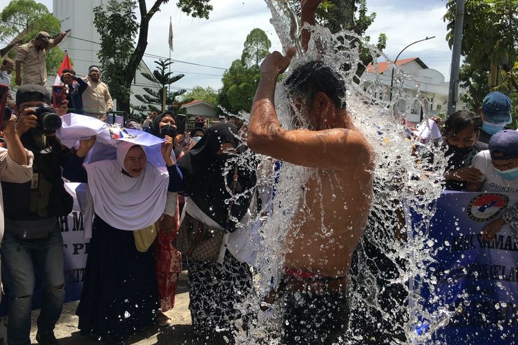 Seorang pengunjuk rasa mandi air laut di depan Kantor Gubernur Sumut, Senin (18/10/2021).